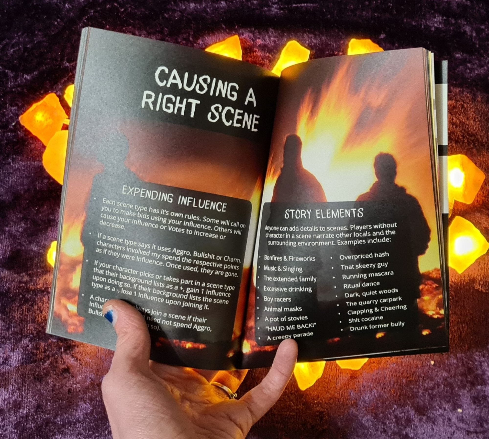 The same background as the book appears on above, but with a hand holding open the pages from below. The spread shows a grainy image of sillowtted people in front of a raging fire. Text boxes over the top describe how scenes are handled.
