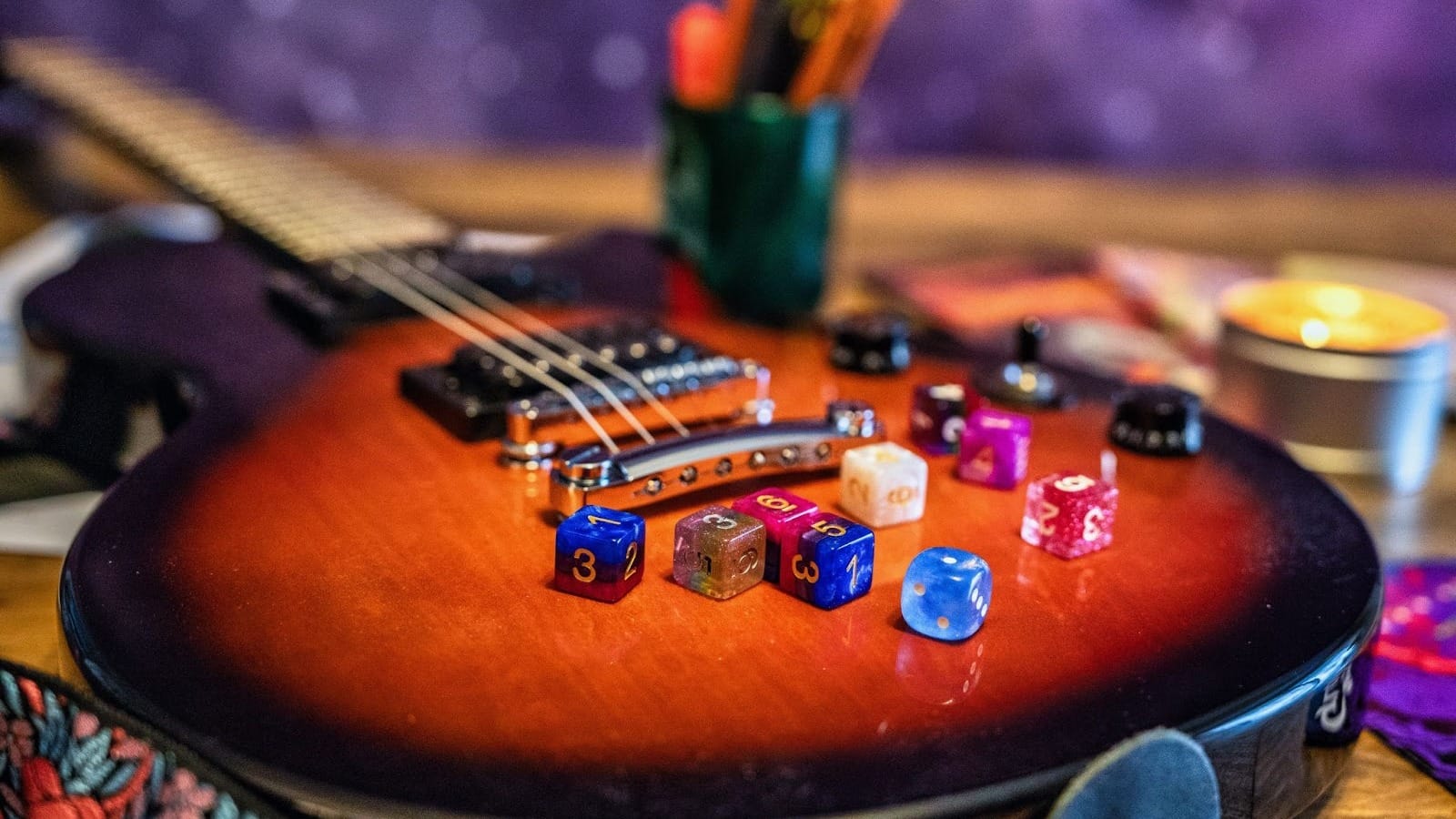 A colorful pile of six-sided dice sit atop an electric guitar.