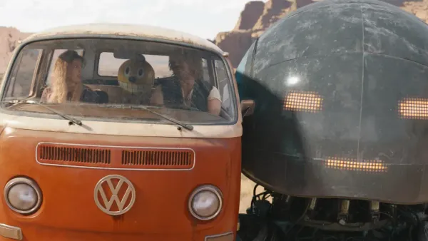 A massive robot holds an orange Volkswagon bus carrying two humans and a smaller yellow robot.