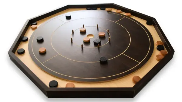 Image of a crokinole board on a white background. black and tan disks sit on a hexagon board made mostly of dark wood.