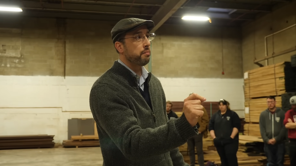 Wyrmwood CEO Doug Costello talks to the company's remaining staff in a warehouse full of wood and table materials.