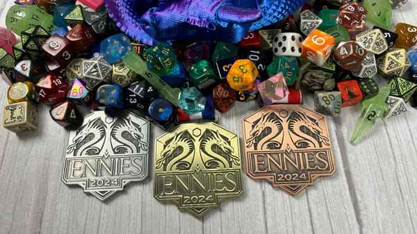 Three ENNIE awards medals (left to right: silver, gold, bronze) sit on a table amidst a motley collection of dice.